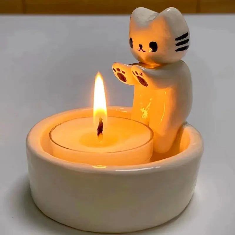 Close-up of the cat tealight holder's paws resting on the candle dish, lit
