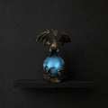 Dragon orb lamp glowing blue on a black shelf against a dark background