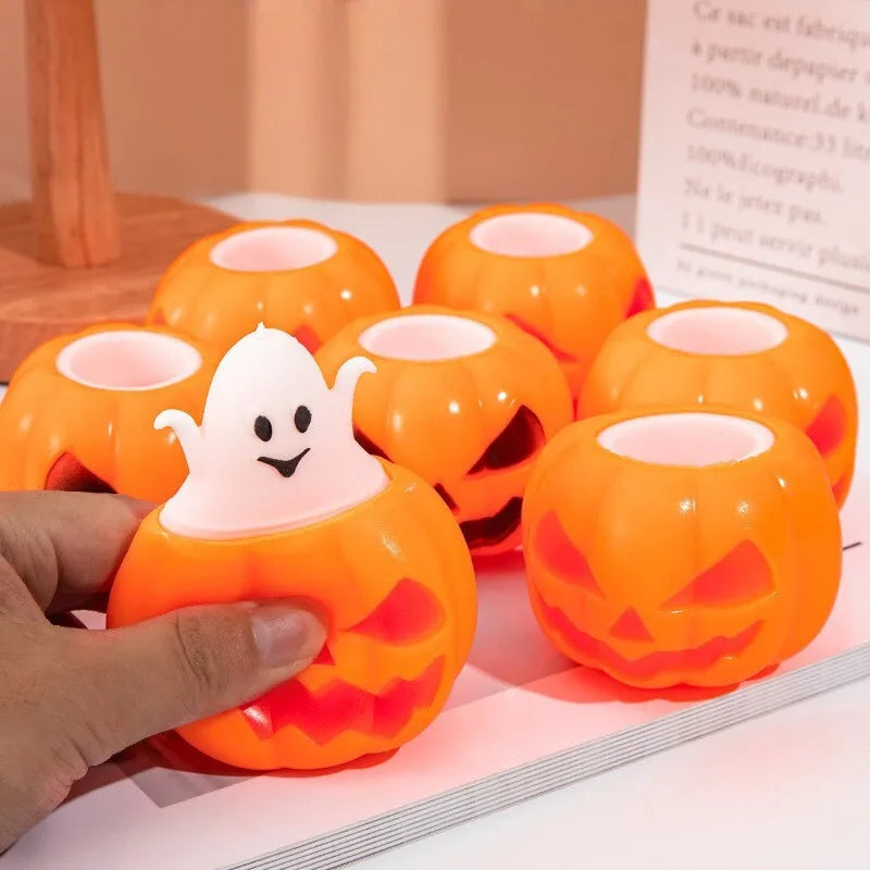 Orange jack-o'-lantern squeeze toy with a small white ghost popping out the top, held in a hand