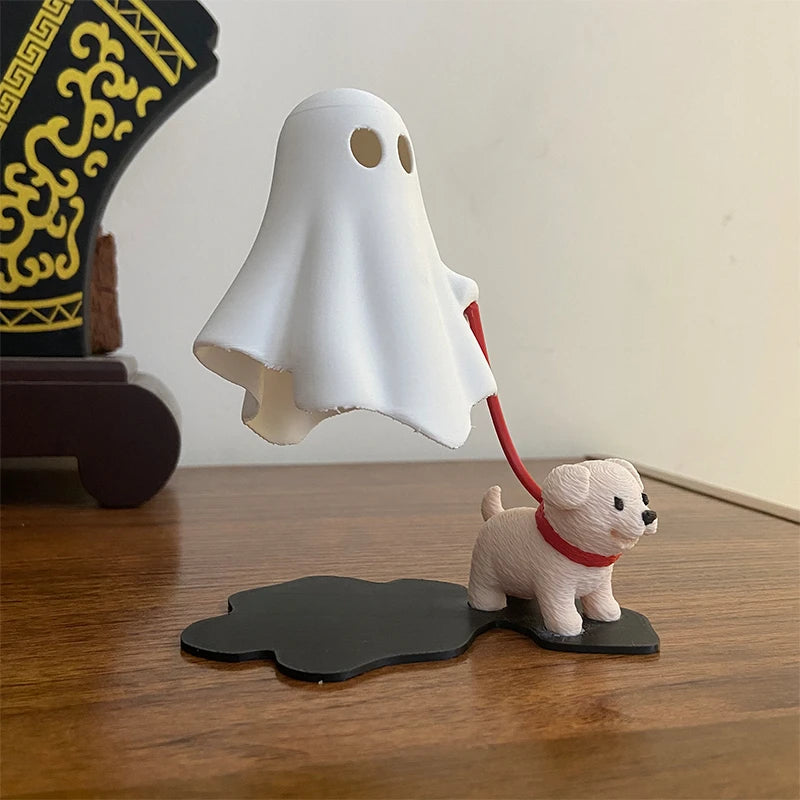 White ghost figurine walking a leashed puppy figurine on a wooden desk