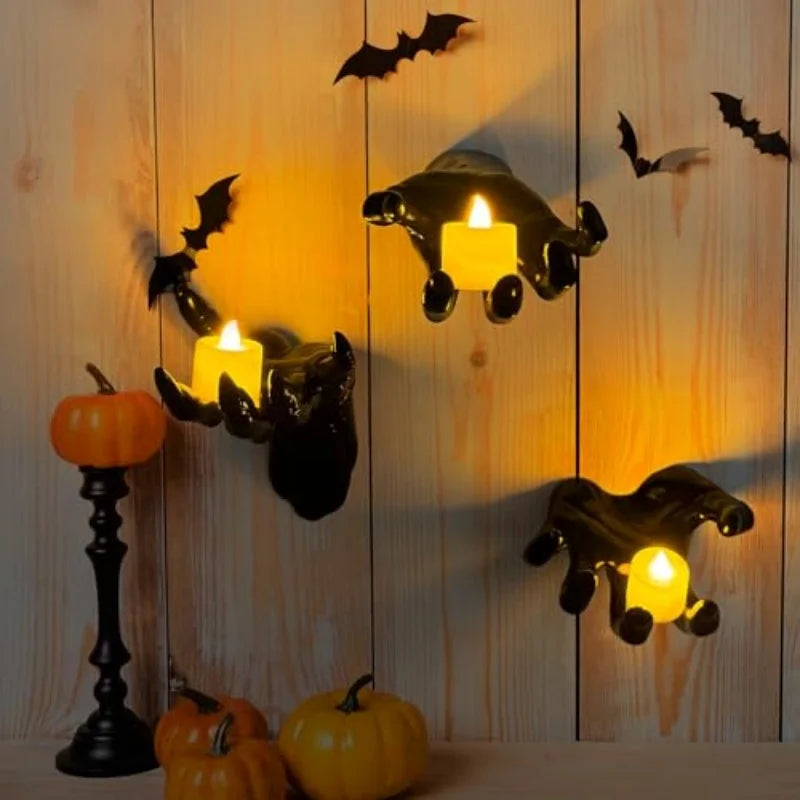 Black hand candle holders mounted on a wooden wall with bat decals and pumpkins