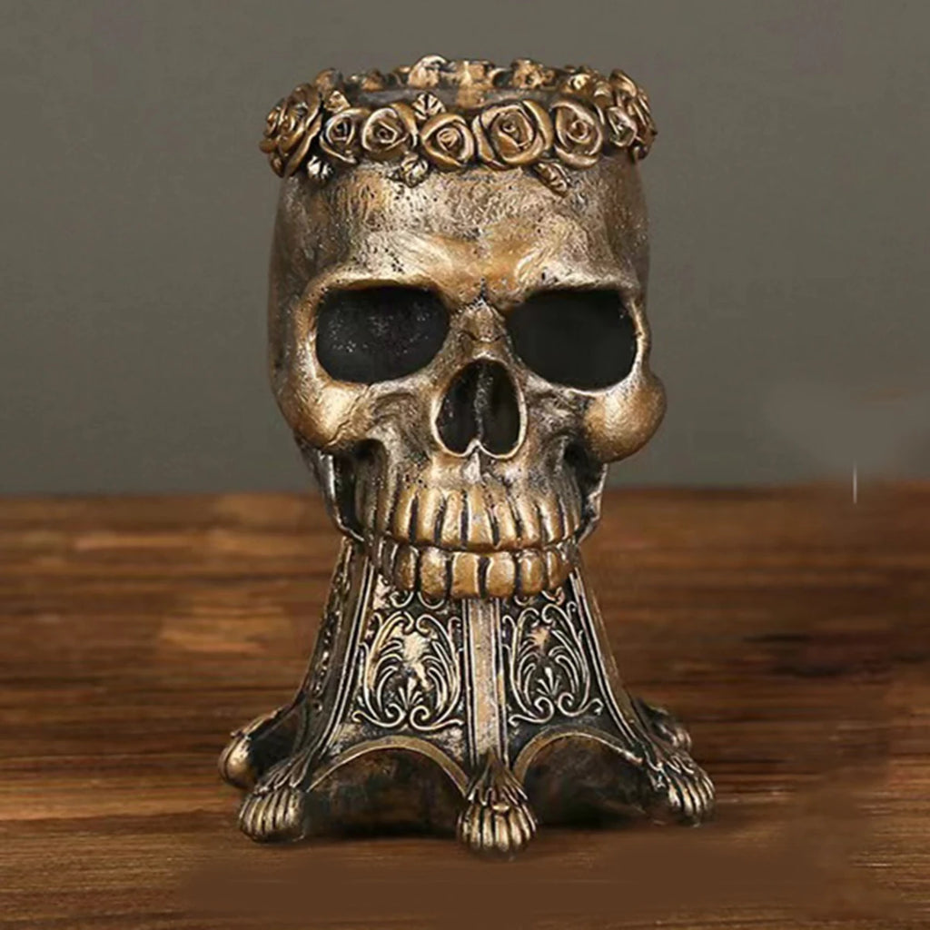 Bronze gothic skull vase with red and pink roses on a wooden table with books