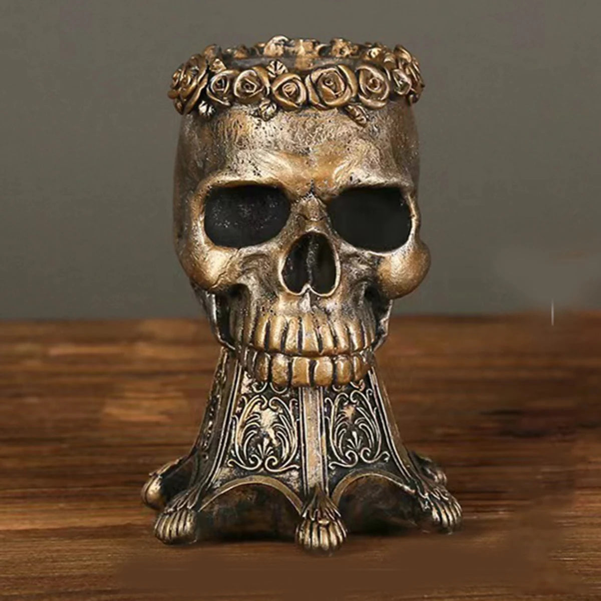 Bronze gothic skull vase with red and pink roses on a wooden table with books