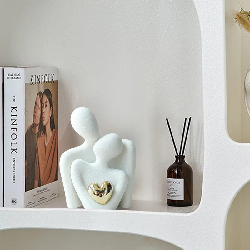 White ceramic Couple Embrace figurine with gold heart accent displayed on a bookshelf