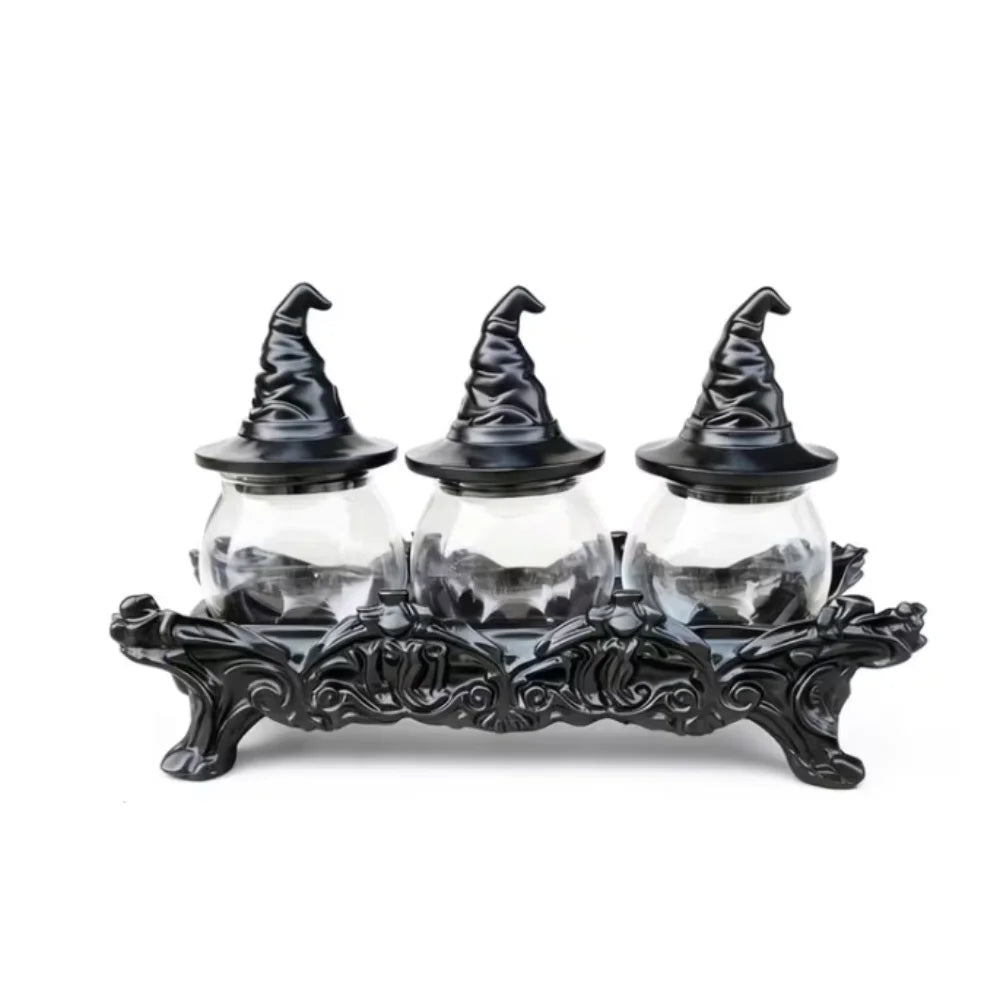 Three glass apothecary jars with black witch hat lids on an ornate stand