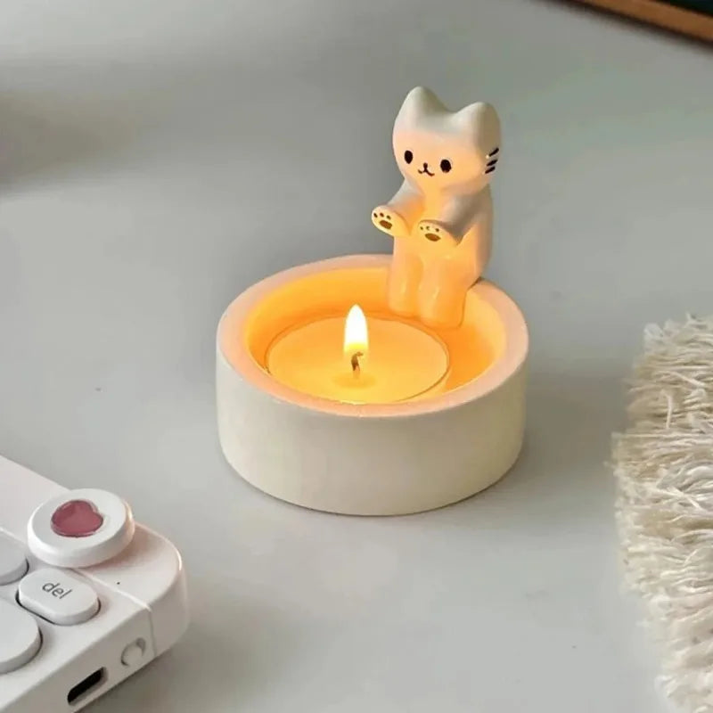 White cat tealight candle holder lit with a warm candle flame on a cozy desk