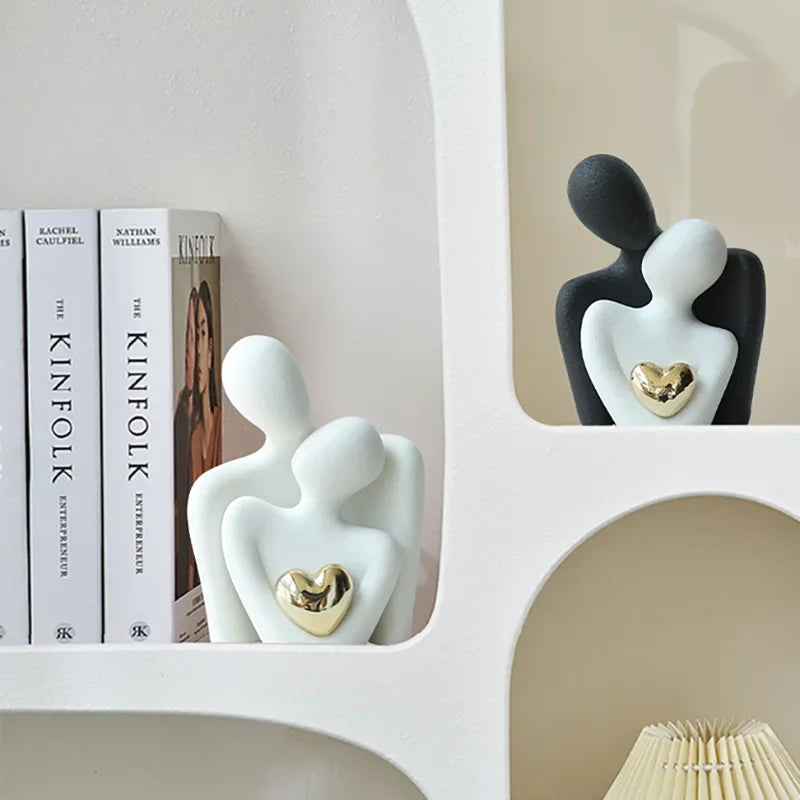 White and black Couple Embrace figurines displayed together on a shelf